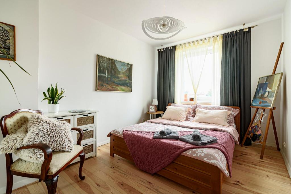 a bedroom with a bed and a chair and a window at Artystyczna przestrzeń przy zabytkowym dworcu in Iława