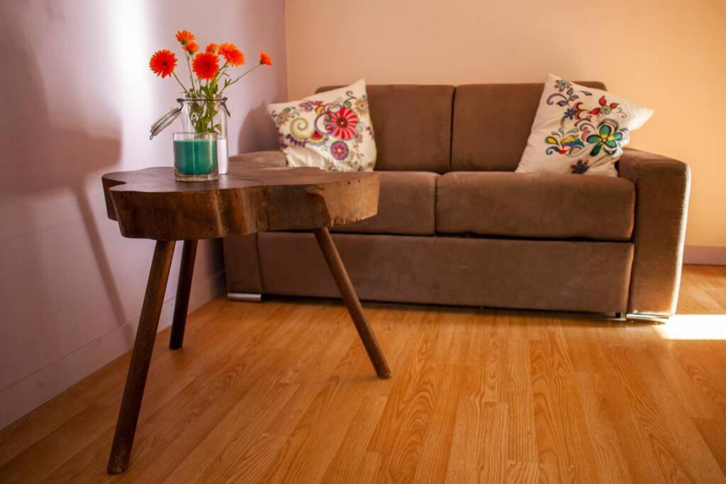 a living room with a couch and a table with flowers on it at La Maison de Dame Holda in Tanville