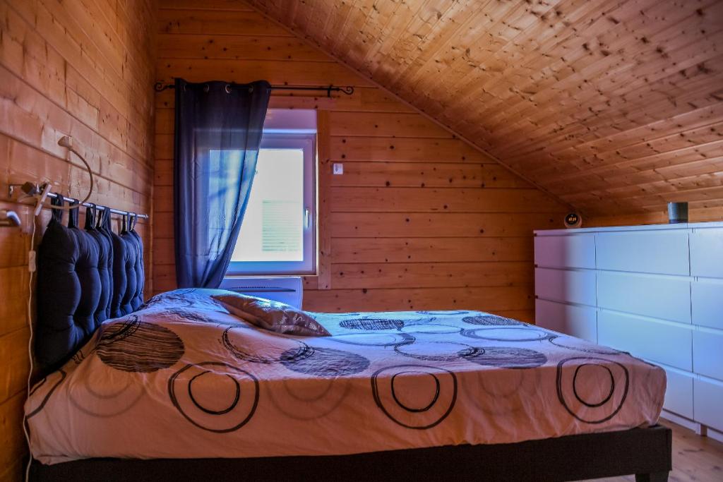 ein Schlafzimmer mit einem Bett in einer Holzhütte in der Unterkunft Insolite maison bois, wifi Netflix, au coeur de l'Argonne et des batailles de Verdun in Chaudefontaine