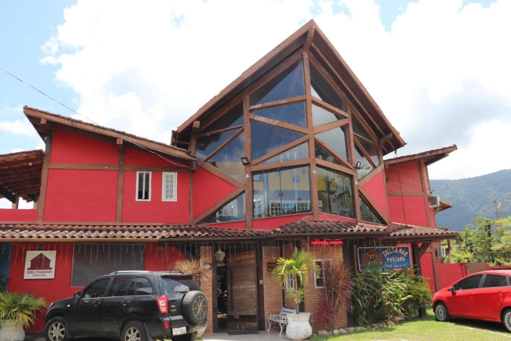 a red house with cars parked in front of it at Pousada Delta Mar Maresias in Maresias