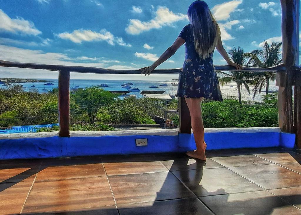 Eine Frau steht auf einem Balkon mit Meerblick in der Unterkunft Galápagos Casa Playa Mann in Puerto Baquerizo Moreno