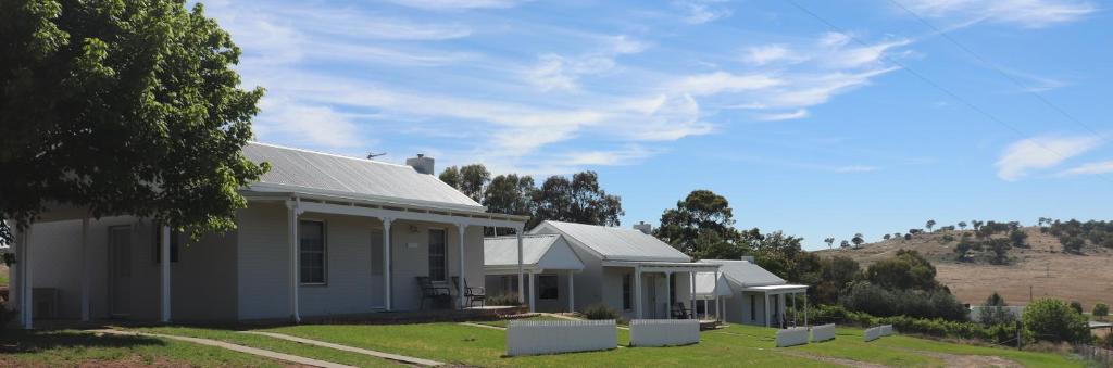 a white house with a hill in the background at Wagga Wagga Country Cottages in Wagga Wagga