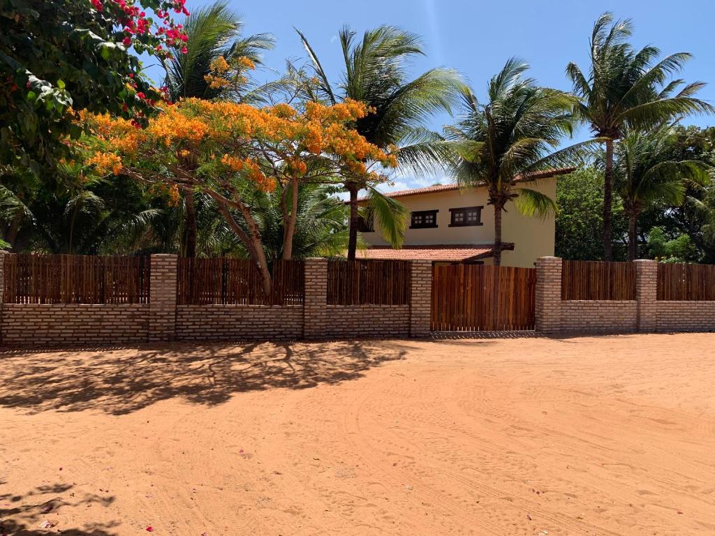 uma cerca em frente a uma casa com palmeiras em Loft Jeri em Jericoacoara
