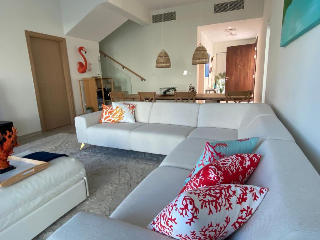 The White villa في الفجيرة: غرفة معيشة مع أريكة بيضاء ووسائد حمراء