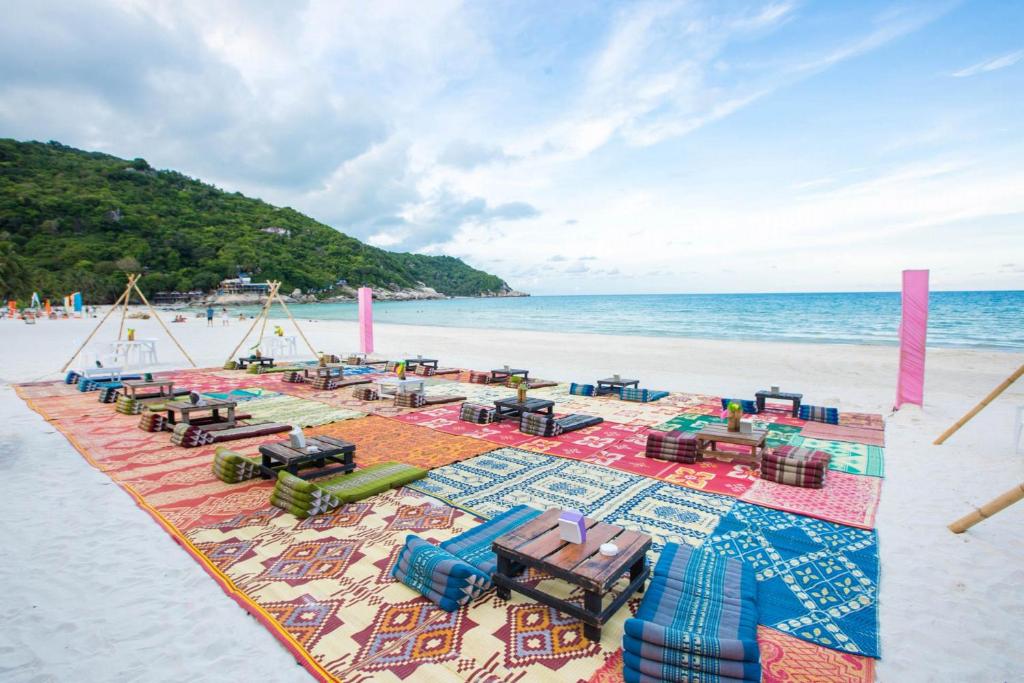 a blanket on a beach with chairs and the ocean at Sunrise Resort- Koh Phangan - SHA Extra Plus in Haad Rin