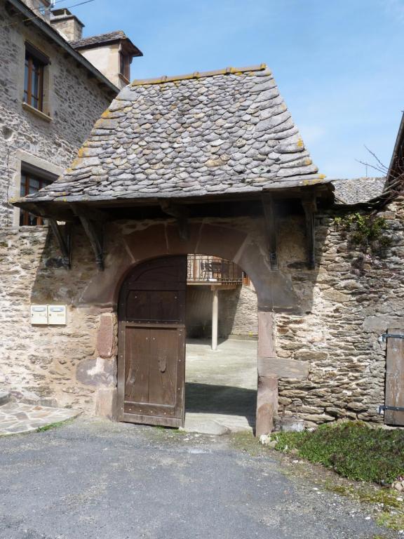 una entrada a un edificio de piedra con puerta de madera en chambre d'hôtes Cadravals Belcastel Aveyron en Belcastel