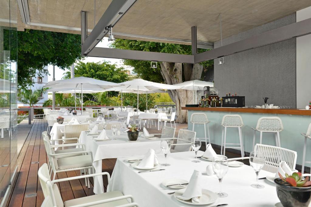 a restaurant with white tables and chairs and umbrellas at Iberostar Heritage Grand Mencey in Santa Cruz de Tenerife