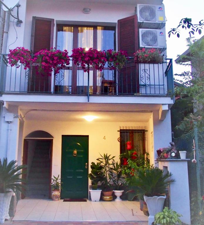 una casa con una puerta verde y flores en un balcón en CASA DEI FIORI, en Somma Lombardo