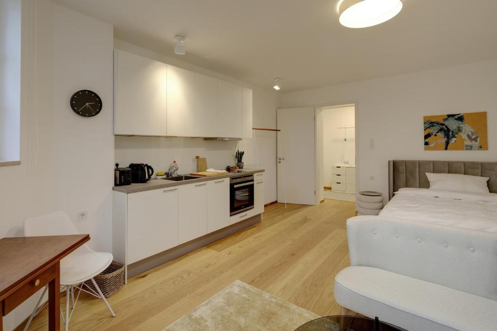 a white bedroom with a bed and a kitchen at Boutique Apartments Freiburg - Elisabeth in Freiburg im Breisgau
