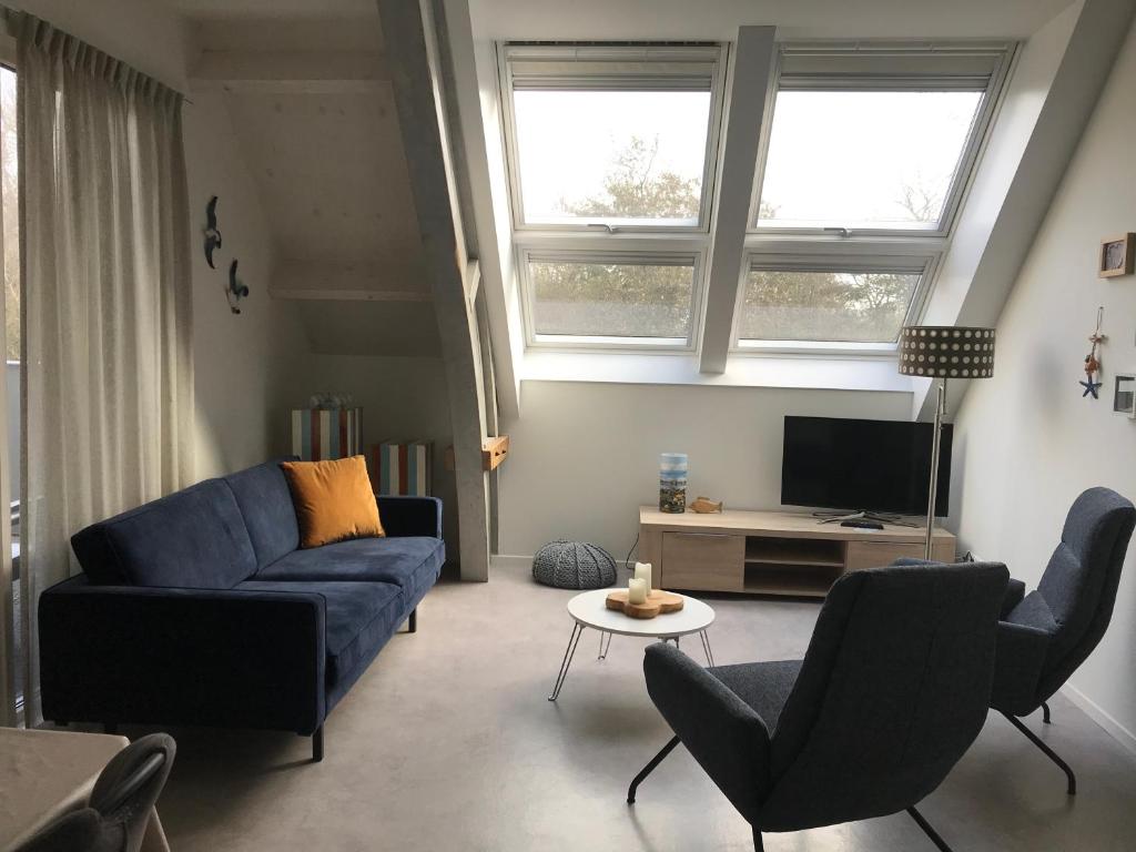 sala de estar con sofá azul y TV en Hendrikhof Appartement 3 ‘het Gebint’ en Westkapelle