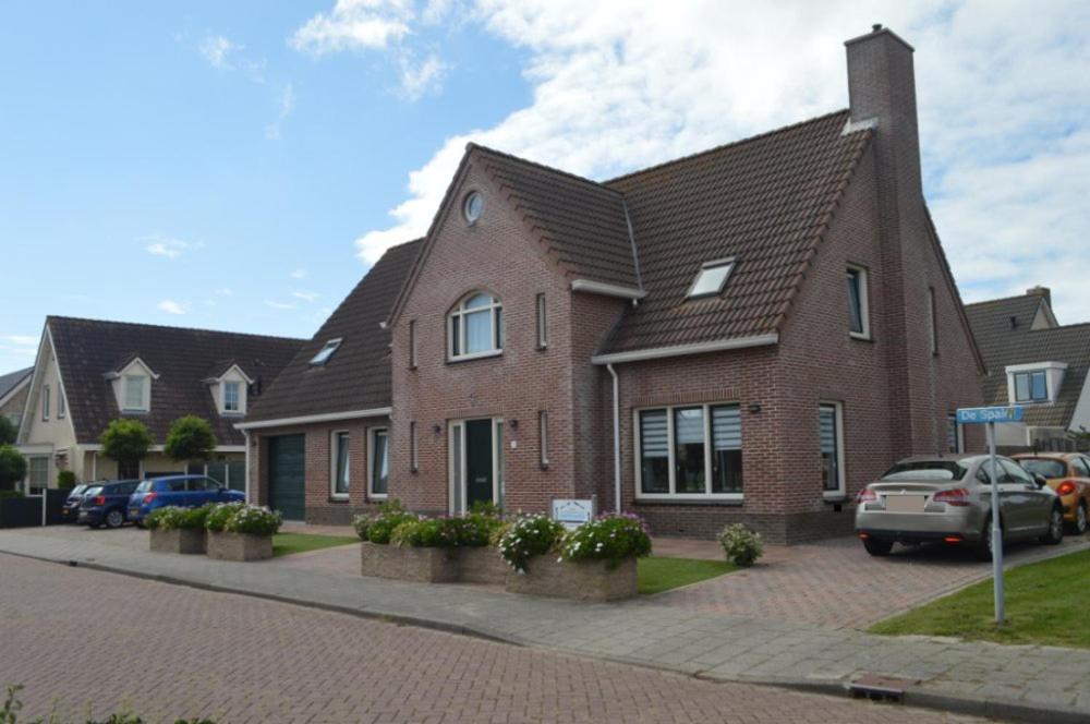 een stenen huis met auto's geparkeerd op een parkeerplaats bij Effe-Zoutelande B&B in Zoutelande
