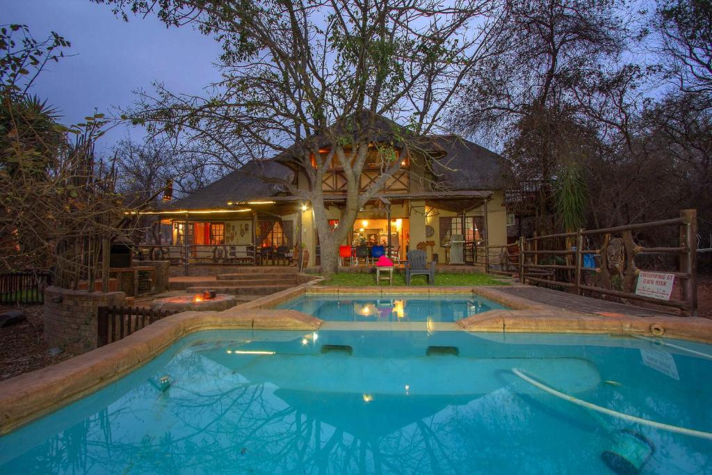 uma casa com piscina em frente a uma casa em Lovely holiday home bordering Kruger National Park em Marloth Park