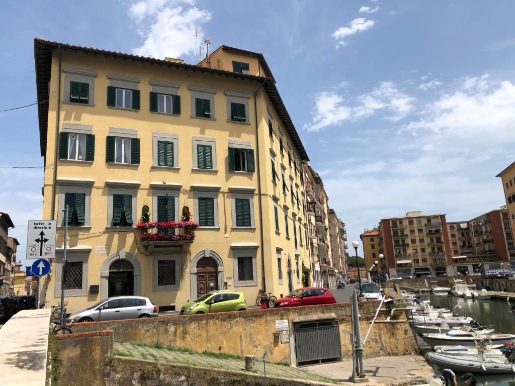 un bâtiment jaune à côté d'un port de plaisance avec des bateaux dans l'établissement Renovated apartment with 3 bedrooms in an historic palazzo between port and old town, à Livourne