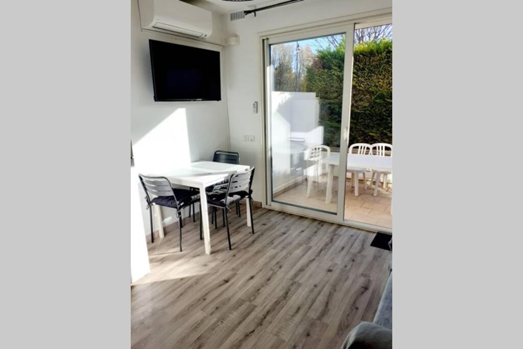 a dining room with a table and a sliding glass door at T2 Rez de chaussée climatisé jardin parking privé in Balaruc-les-Bains