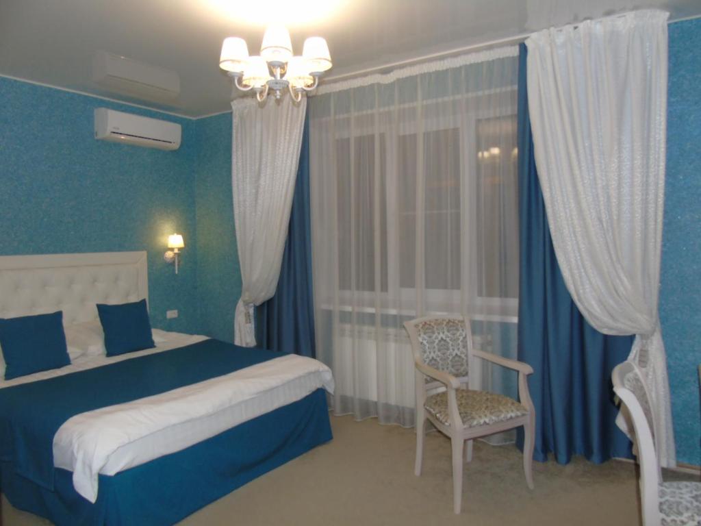a blue bedroom with a bed and a chair at Domashny Ochag in Ukhta