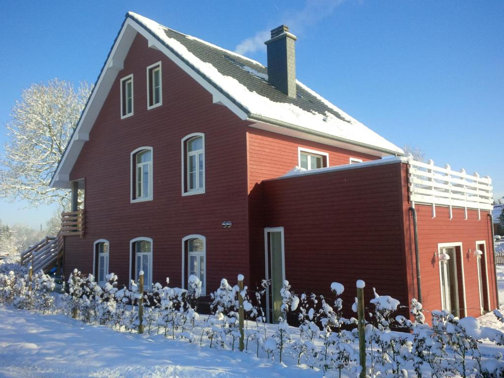 una gran casa roja con nieve en el suelo en Rod Hus en Sourbrodt