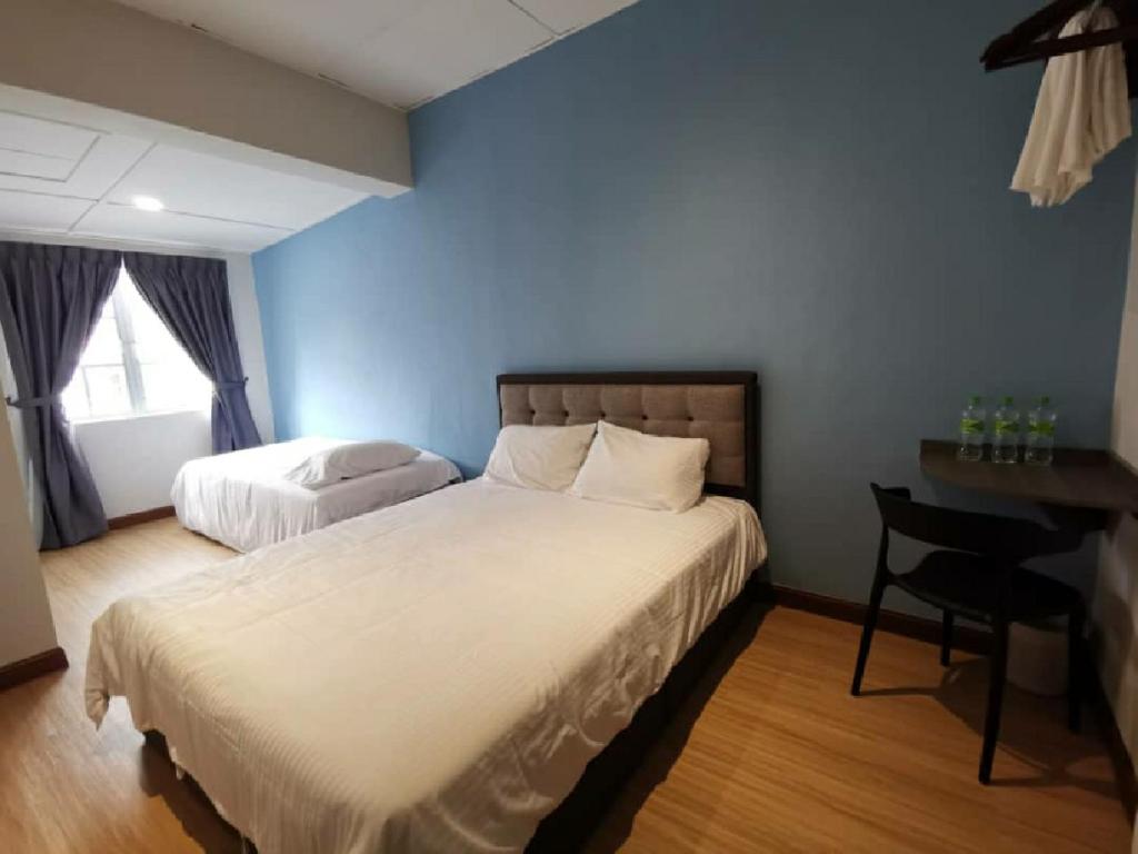 a bedroom with two beds and a desk with a desk at MOON HOTEL in Brinchang