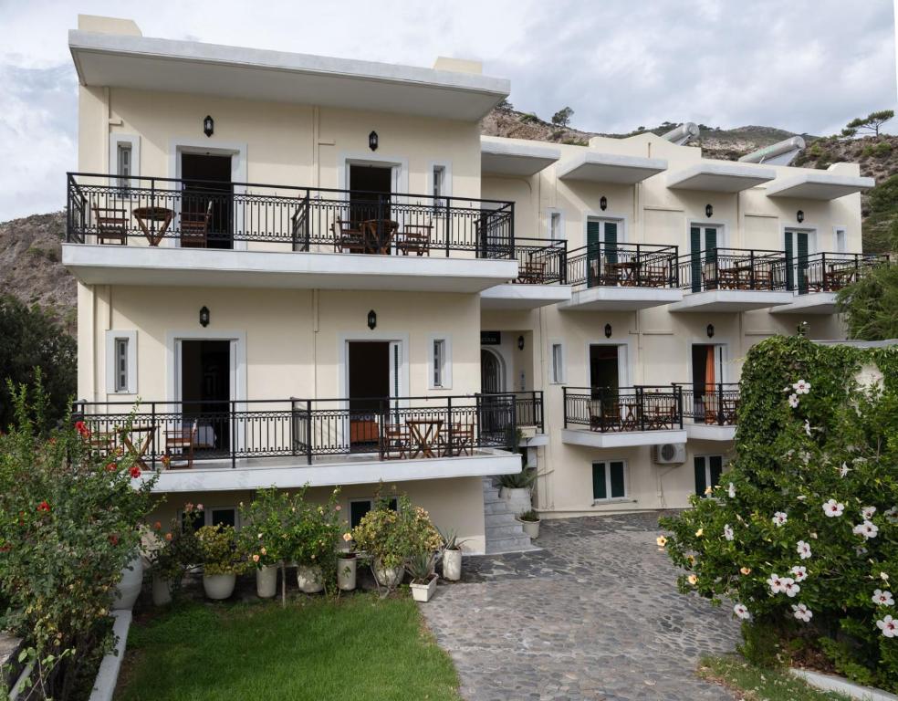 a large white building with balconies and a yard at Aretousa in Sougia
