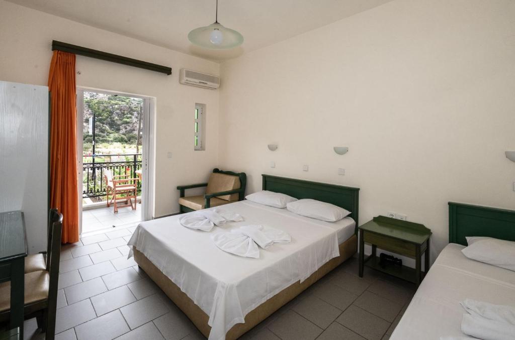 a bedroom with two beds and a balcony at Aretousa in Sougia