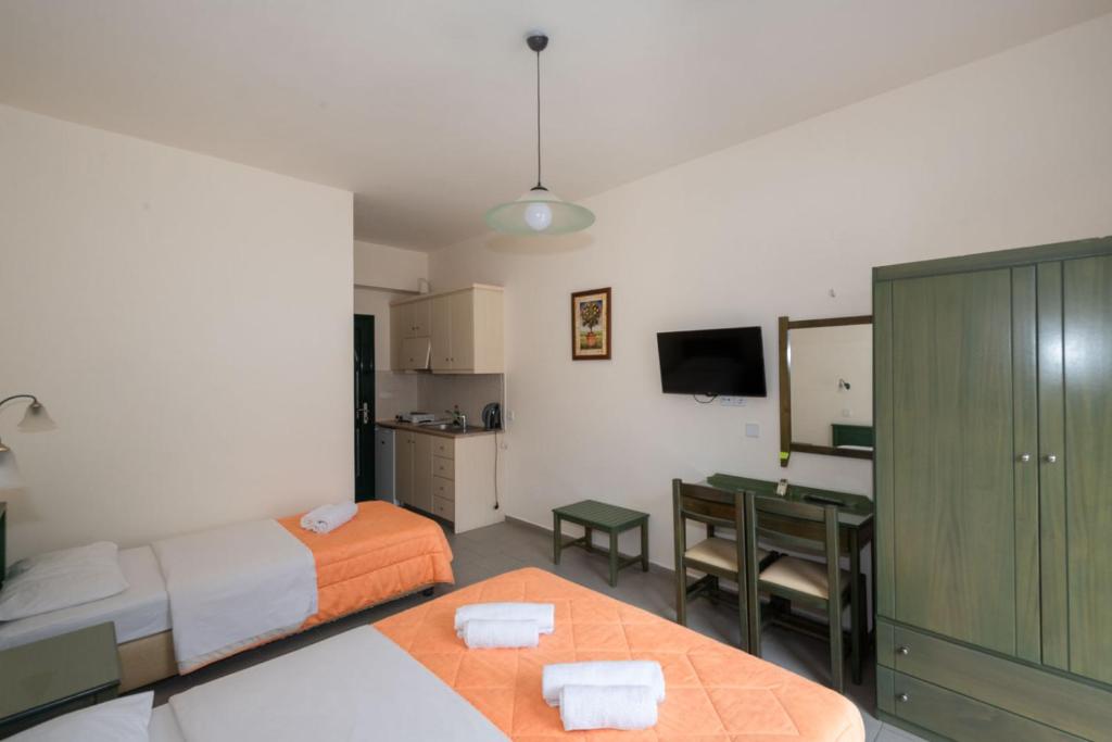 a bedroom with two beds and a desk with a mirror at Aretousa in Sougia