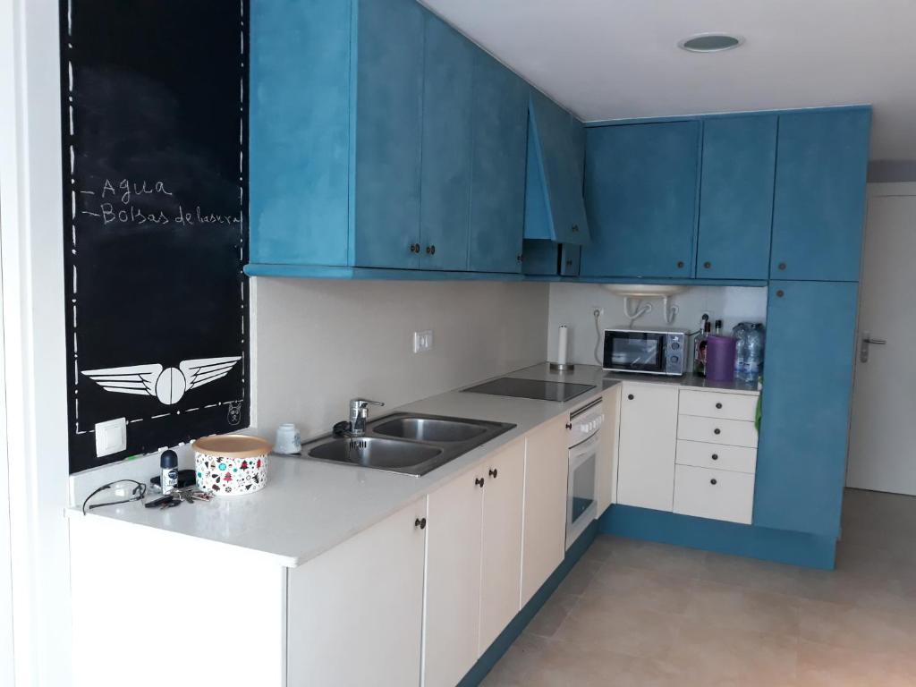 una cocina con armarios azules y fregadero en Apartamento en la costa brava, en Palafrugell