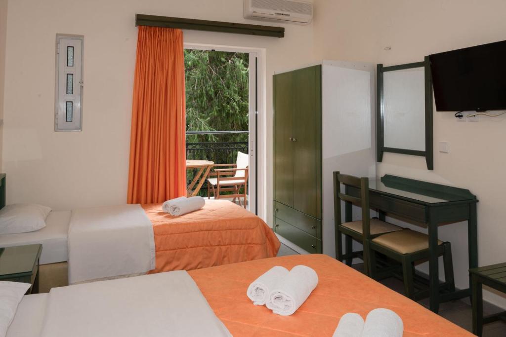 a hotel room with two beds and a table with towels at Aretousa in Sougia