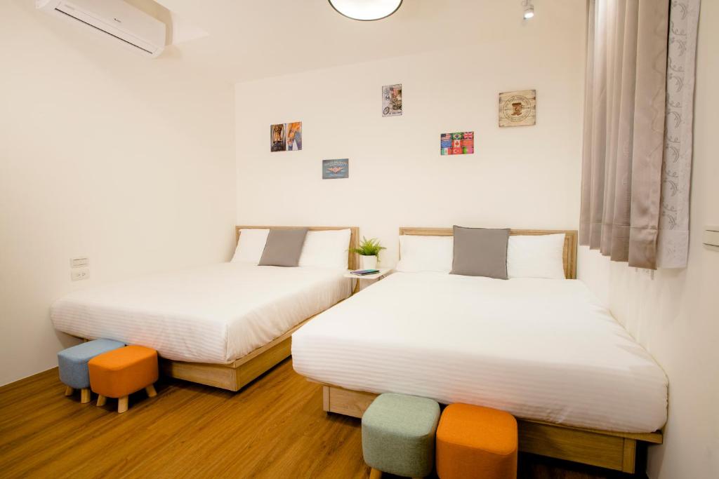 two beds in a room with white sheets at Xiao Dong Quiao Yu in Yilan City