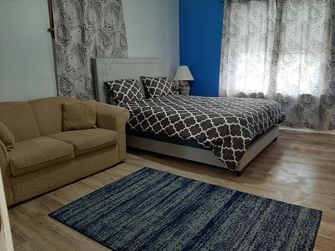 1 dormitorio con cama, sofá y alfombra en Close to center, en Winnipeg