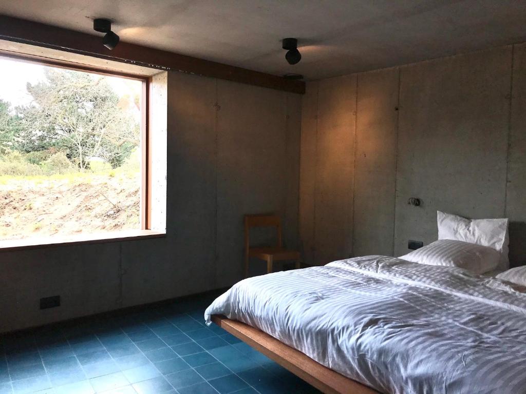 a bedroom with a large bed and a window at rodune in Koksijde