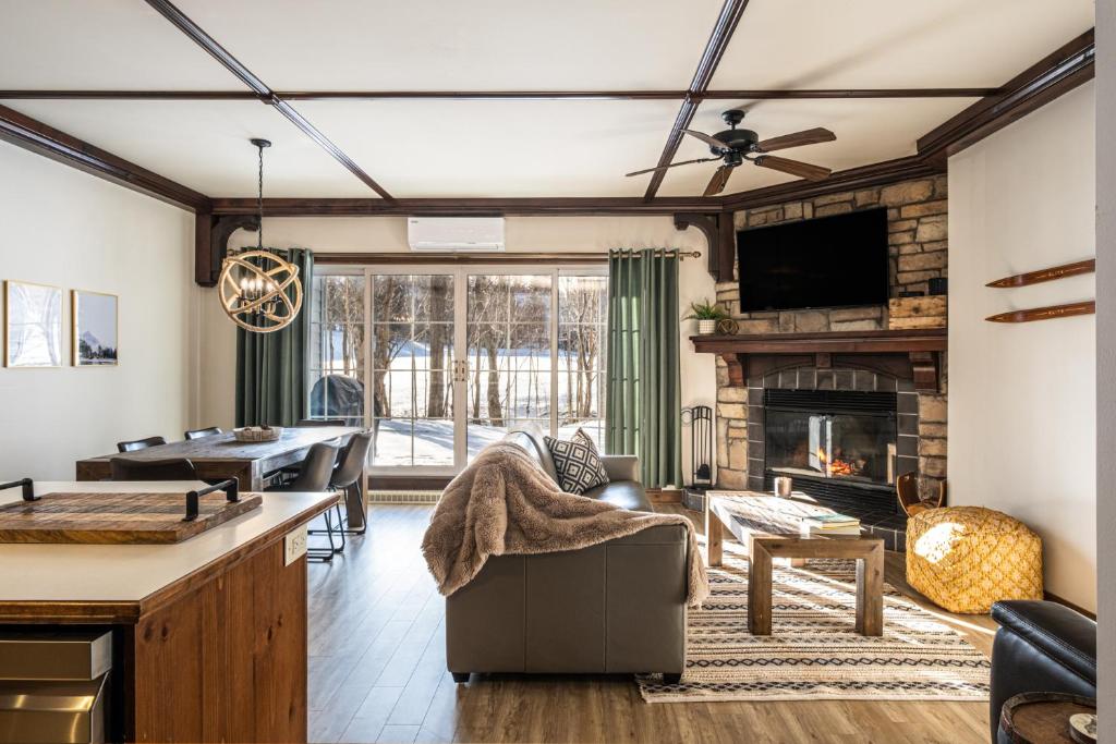 a living room with a couch and a fireplace at Le Sous-Bois (Les Manoirs) Mont-Tremblant in Mont-Tremblant