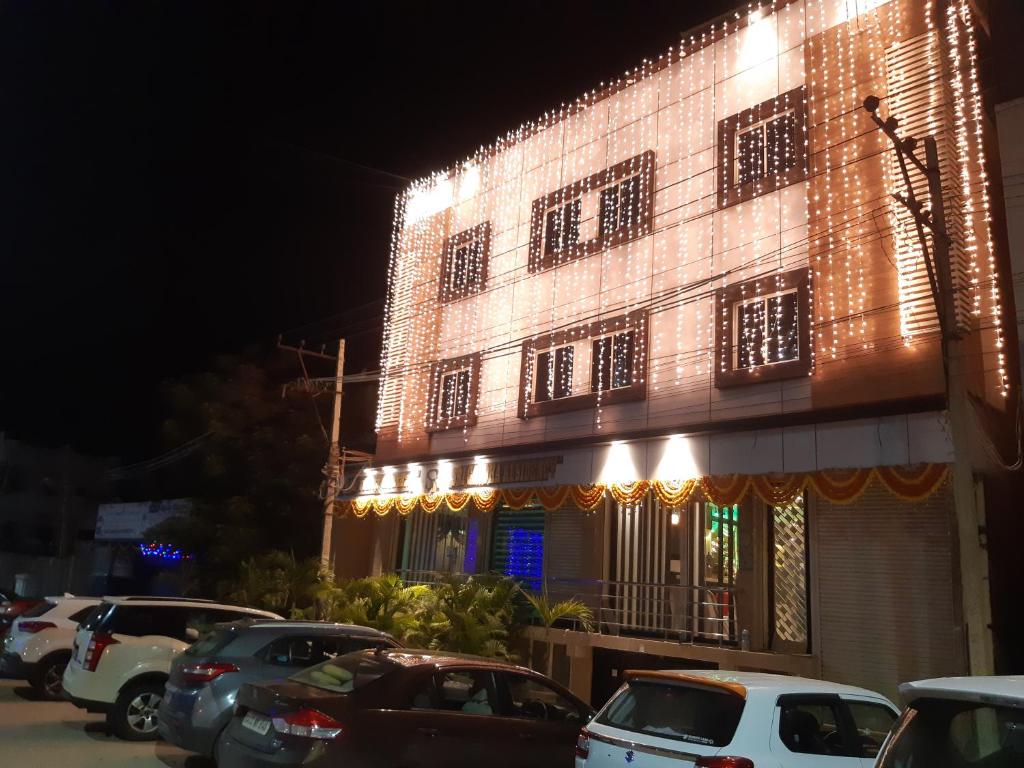 a lit up building with cars parked in front of it at Srigandha Residency "Vaccinated Staff" in Dāvangere