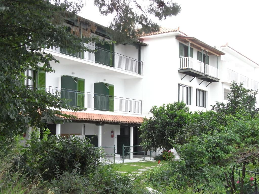 a white building with green windows and trees at Villa Yiannis (Adult Friendly) in Megali Ammos