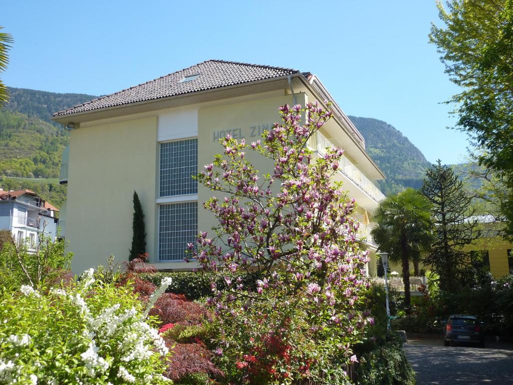 a house with a flowering tree in front of it at Hotel Zima in Merano