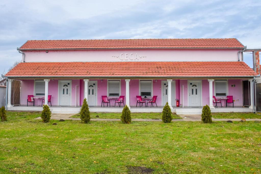 a pink house with tables and chairs in a yard at Guest House Ceca in Melenci