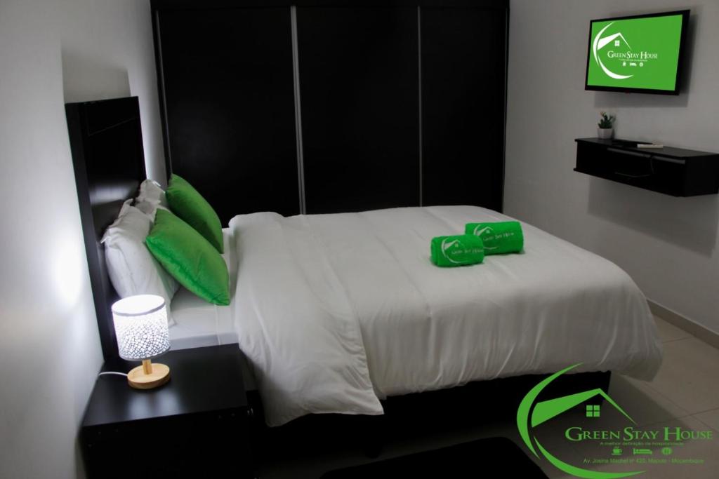 um quarto com uma cama branca e almofadas verdes em Green Stay house em Maputo