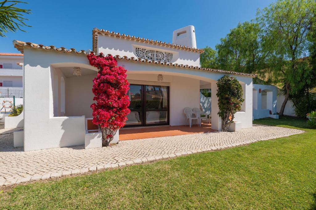 Oura Family House في ألبوفيرا: منزل أبيض مع مجموعة من الزهور الحمراء