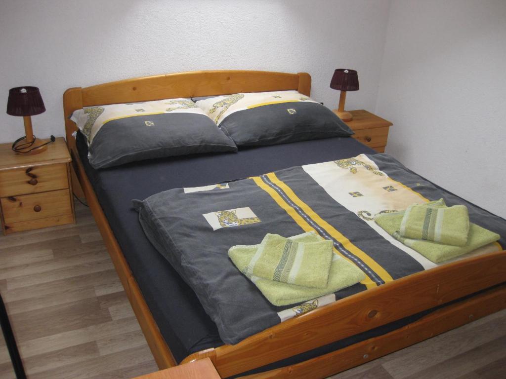 ein Bett mit blauer Bettwäsche und grünen Kissen darauf in der Unterkunft Rent a Scooter Vendégház in Zamárdi