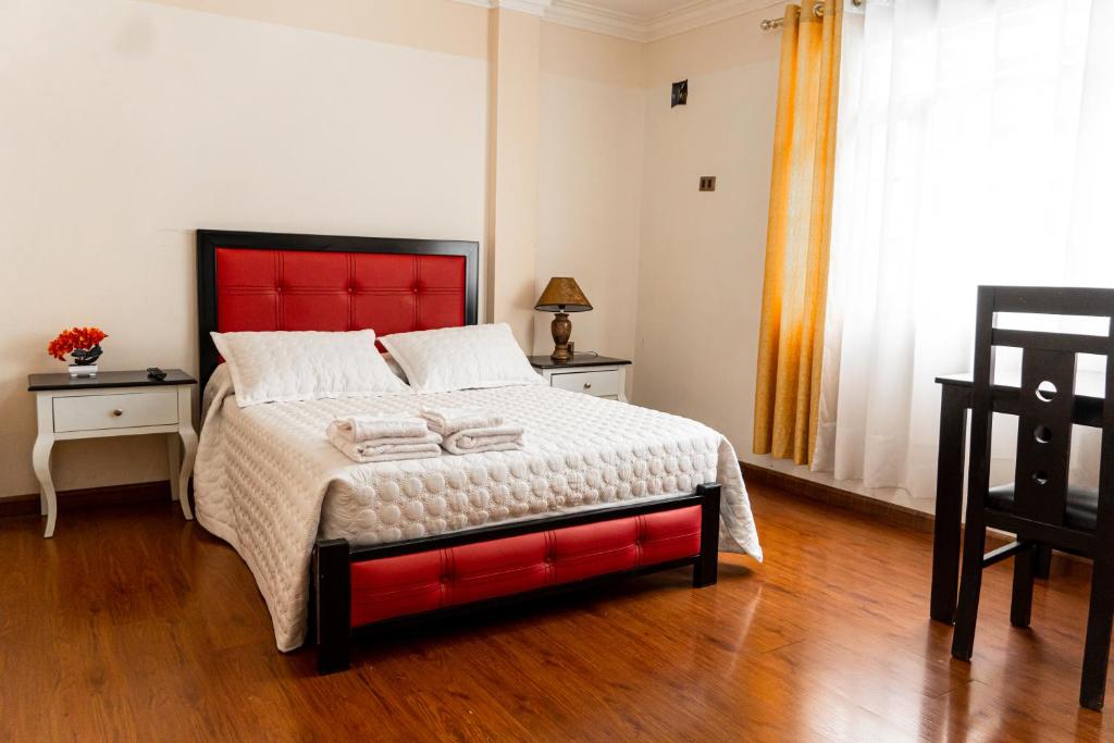a bedroom with a large bed with a red headboard at Residencial Velia & Victoria in Cochabamba