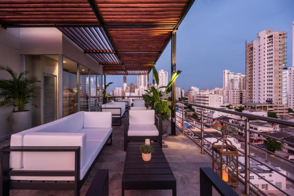 卡塔赫納的住宿－Oz Hotel Luxury，屋顶庭院配有白色家具,享有城市美景。