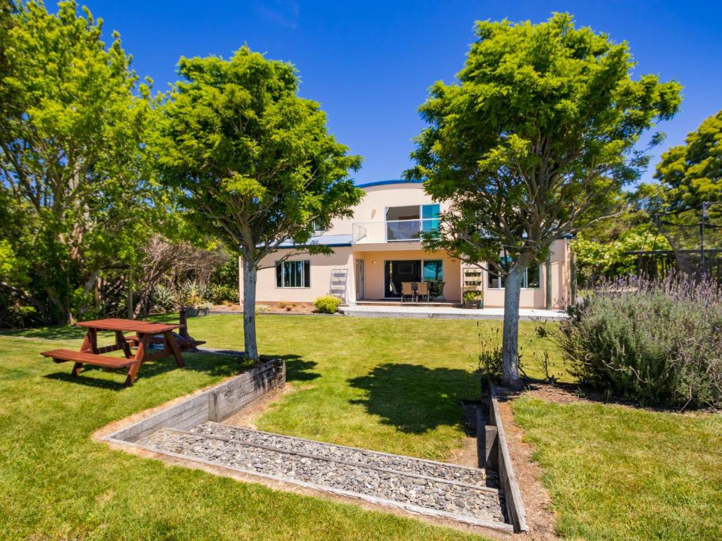 a garden with a picnic table and trees at La Casa Al Mare - Golden Bay Beach House in Tasman