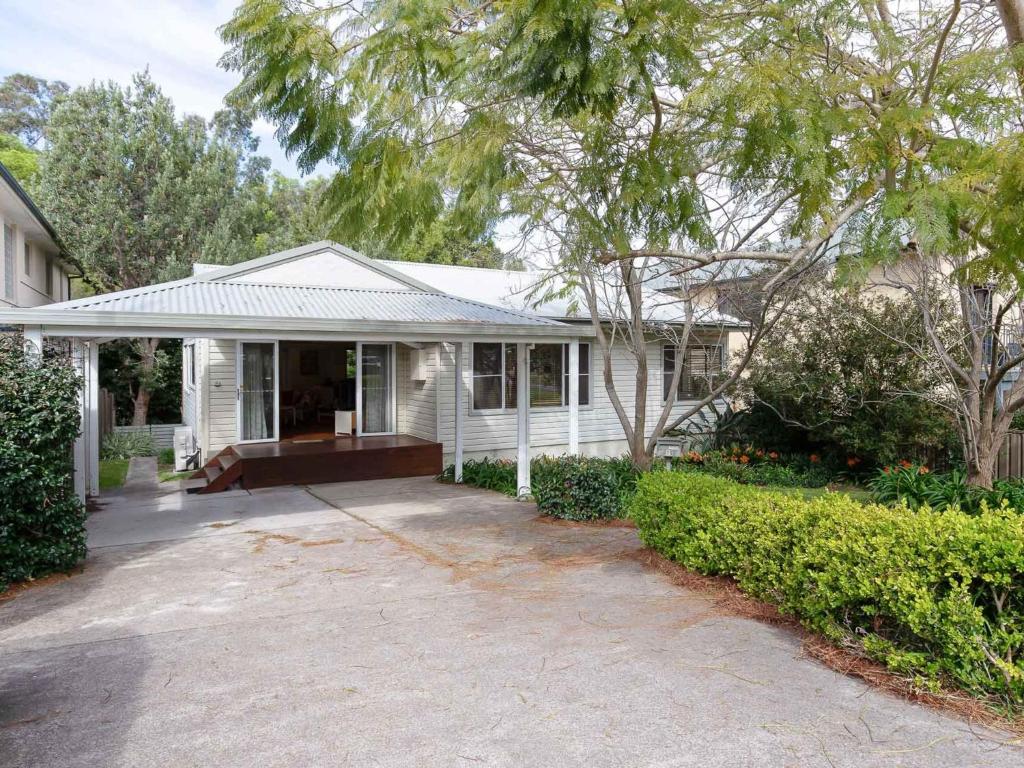 ein weißes Haus mit einer Veranda und einer Auffahrt in der Unterkunft Dutchies Haven, 11 Christmas Bush Ave - Pet friendly, large enclosed yard, air con and Wi-Fi in Nelson Bay