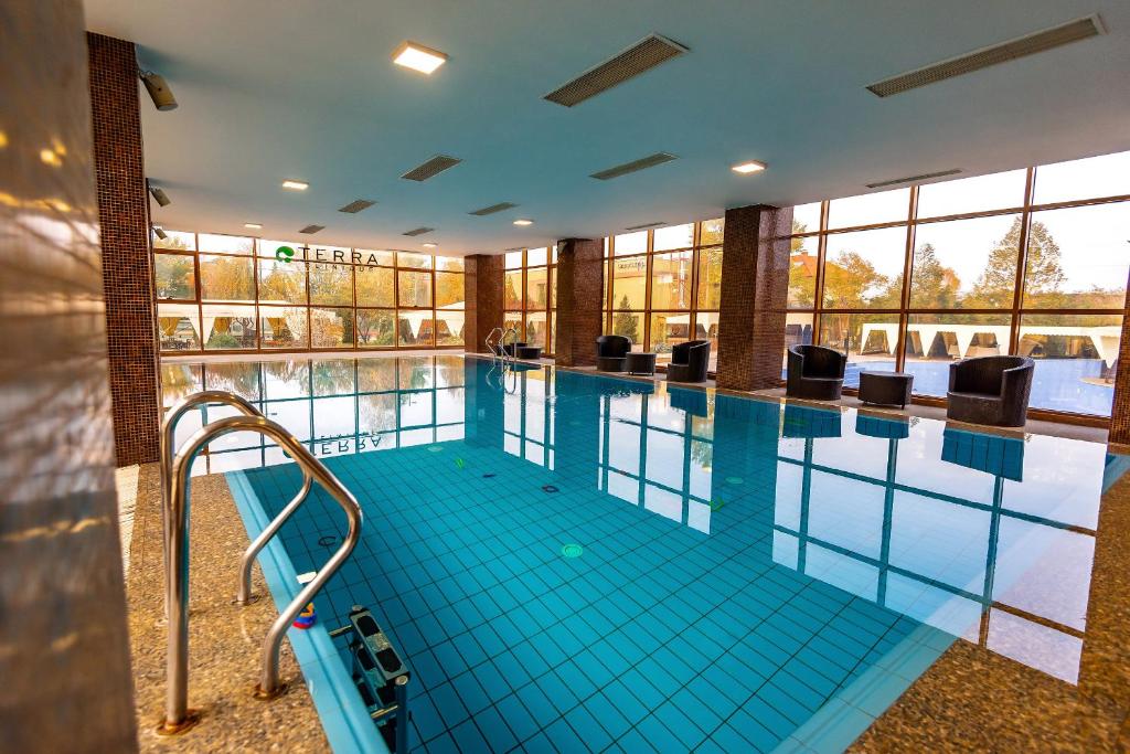 una gran piscina con suelo de baldosa azul y ventanas en Hotel Terra Balneo&Spa, en Galaţi
