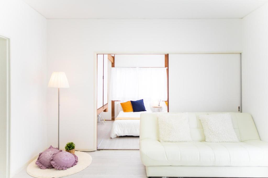 een witte woonkamer met een witte bank en een bed bij Takashima Lakeside Resort in Takashima