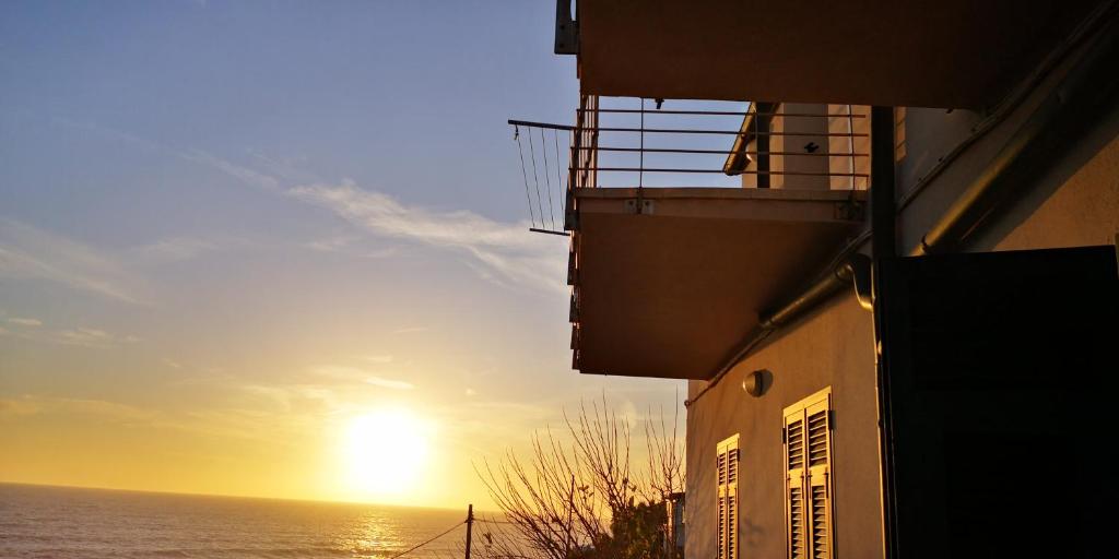 um pôr-do-sol sobre o oceano a partir de um edifício em Casa da Brunetto em Costarainera