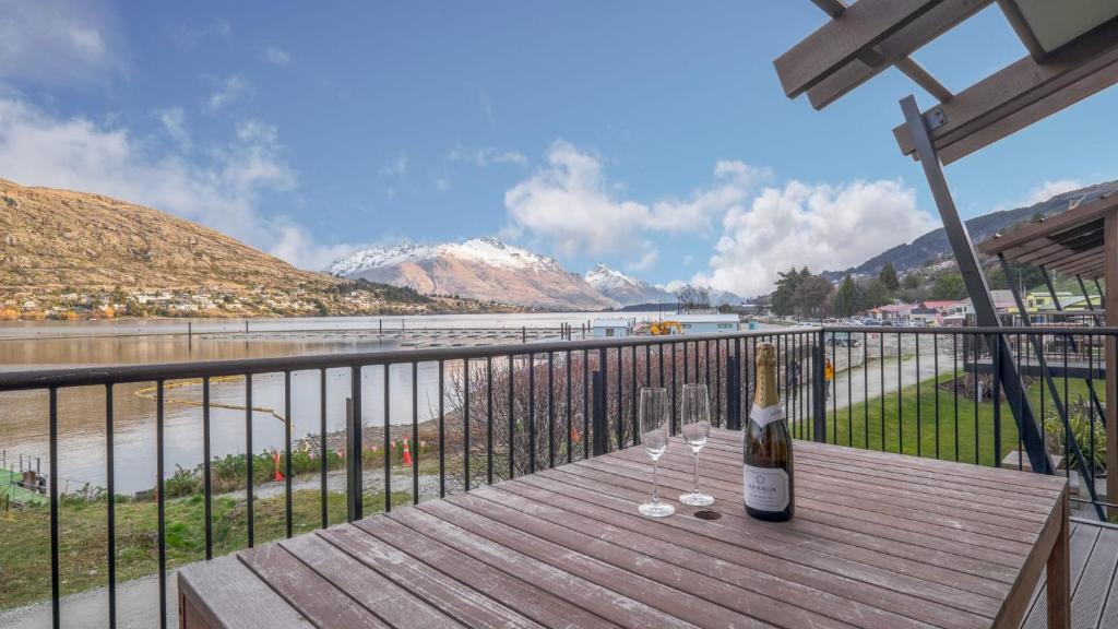 a bottle of wine sitting on a wooden table on a balcony at Marina Views - Apt 207 in Queenstown