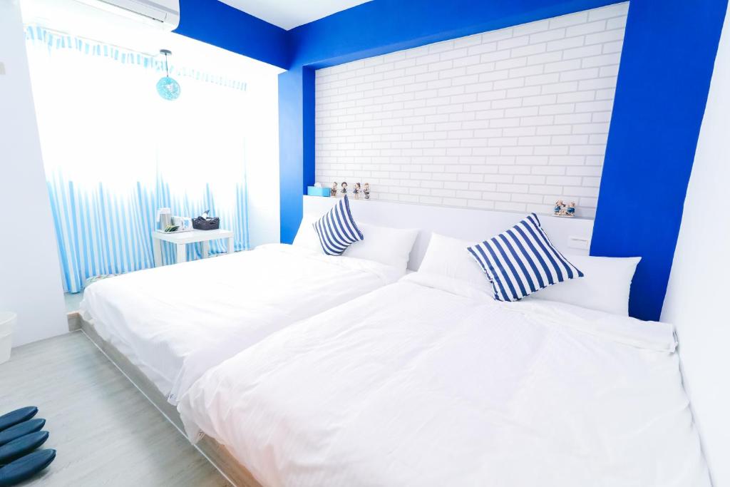 2 weiße Betten in einem Schlafzimmer mit blauen Wänden in der Unterkunft 逢甲blue house in Taichung