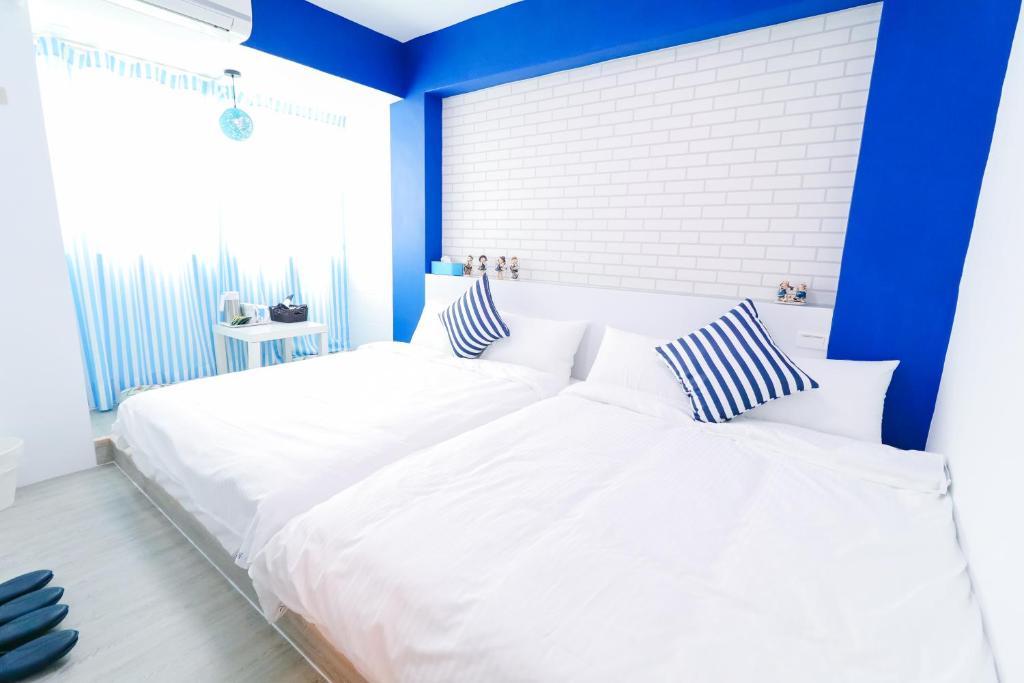 two white beds in a bedroom with blue walls at Long house in Taichung
