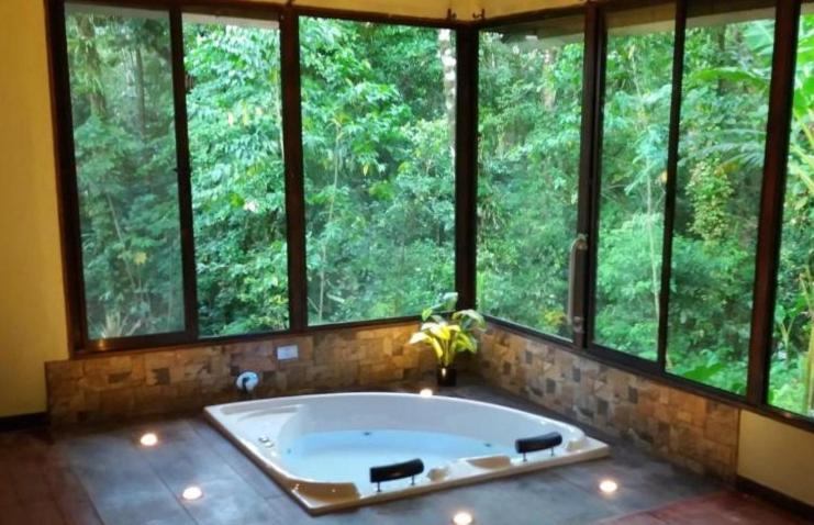 bañera grande en una habitación con ventanas en Tropical Suites & Villas, en Fortuna