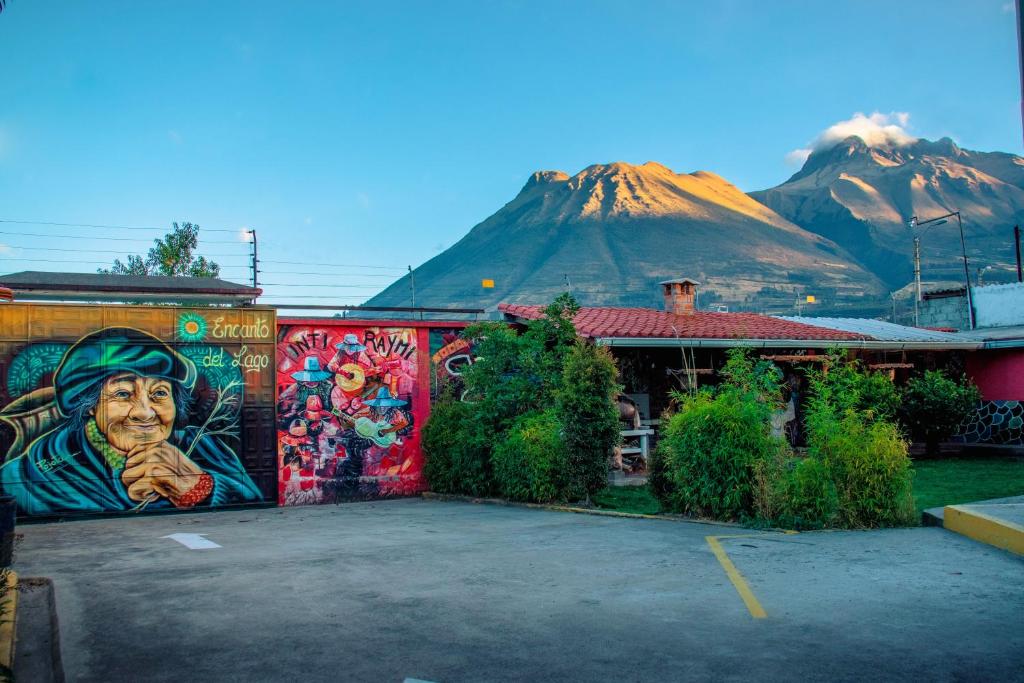 un edificio cubierto de graffiti con montañas al fondo en Hospedaje encanto del lago, en González Suárez