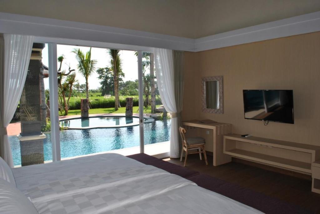 a bedroom with a bed and a view of a pool at Kori Maharani Villas - Lagoon Pool Access 3 in Siyut
